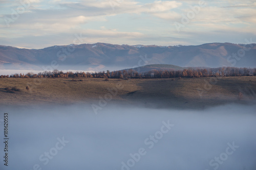 Fototapeta Naklejka Na Ścianę i Meble -  A ridge sticking up out of the fog to bask in the last rays of sun