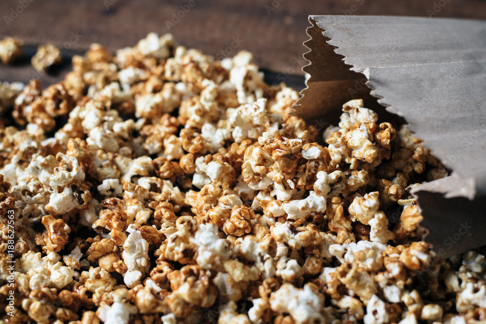 fresh caramel popcorn in a paper bag on wooden table