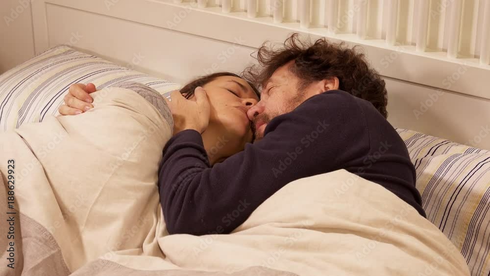 Man entering in bed at night kissing wife romantic moment closeup slow motion Man entering in bed at night kissing wife romantic moment closeup slow motion