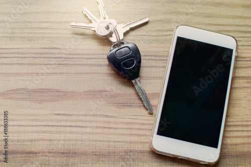 Smart phone with blank screen and car remote alarm control key on the wooden table
