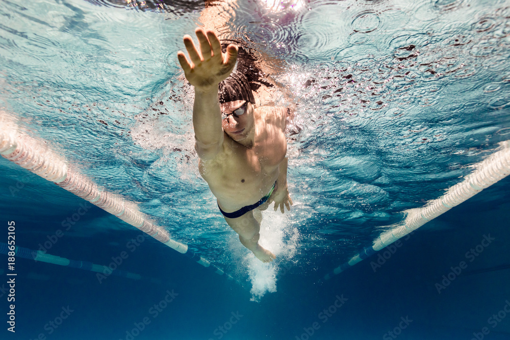 underwater picture of young swimmer in goggles exercising in swimming pool - obrazy, fototapety, plakaty 