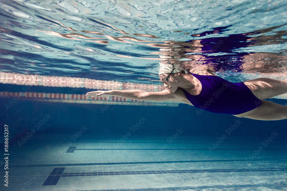 underwater picture of young female swimmer exercising in swimming pool - obrazy, fototapety, plakaty 