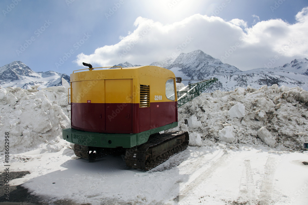 A view of a snow machine with a crane in the snow covered landscape in the alps switzerland