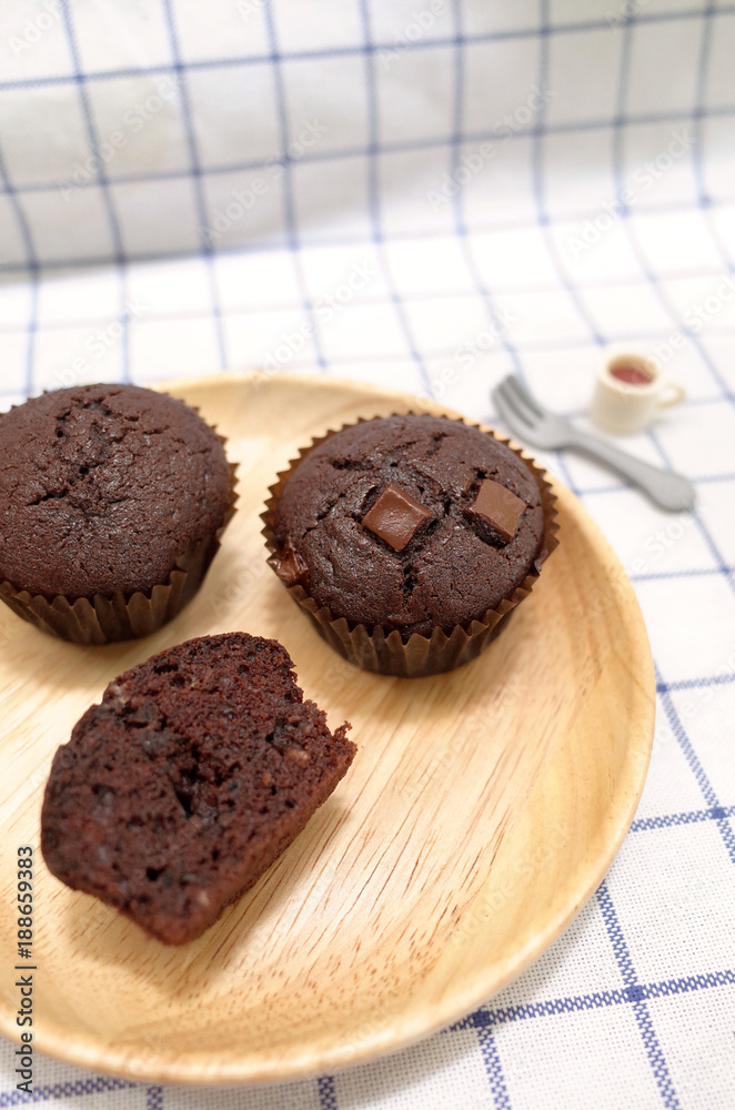 Homemade Chocolate Cupcake and Half Piece ready to Serve on Wooden Plate with Tiny Toy Folk and Cup