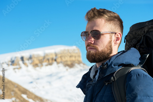 A hipster traveler with a beard wearing sunglasses in nature.