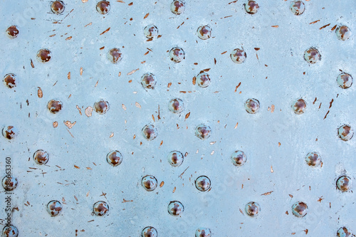Gray metal wall with rusty spots and rivets. Abstract textured background.
