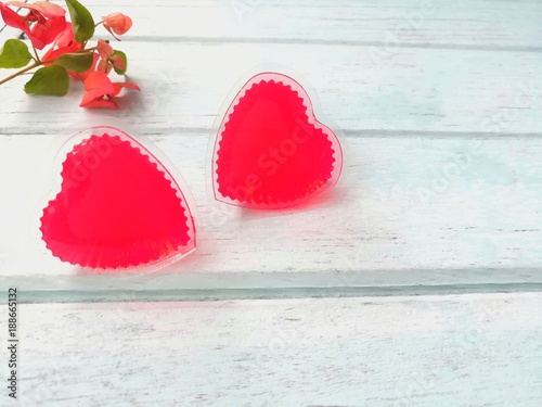 Fototapeta Naklejka Na Ścianę i Meble -  Couple cute red hearts made of jelly with red flowers on blue wooden background, love is beautiful, Valentine day