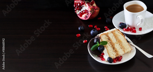 Piece of layer cake with fresh blueberries, cream cheese and chocolate cookies. Dark wooden background. Romantic Valentine's Day concept.