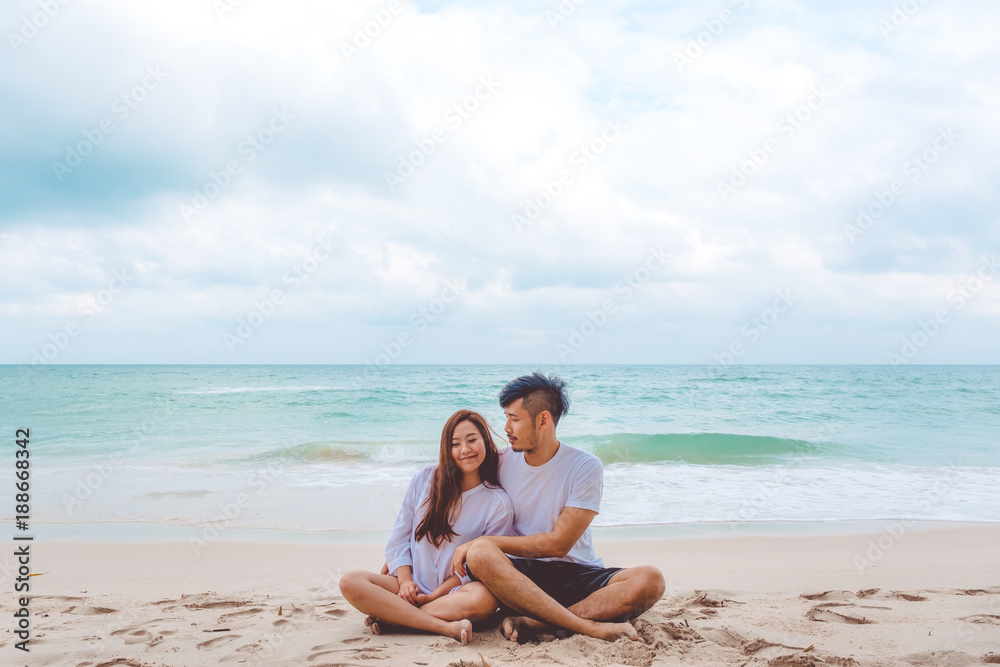 Portrait image of a lover couple sitting on the beach and looking at each other with feeling loved , the sea and blue sky background Portrait image of a lover couple sitting on the beach and looking at each other with feeling loved , the sea and blue sky background