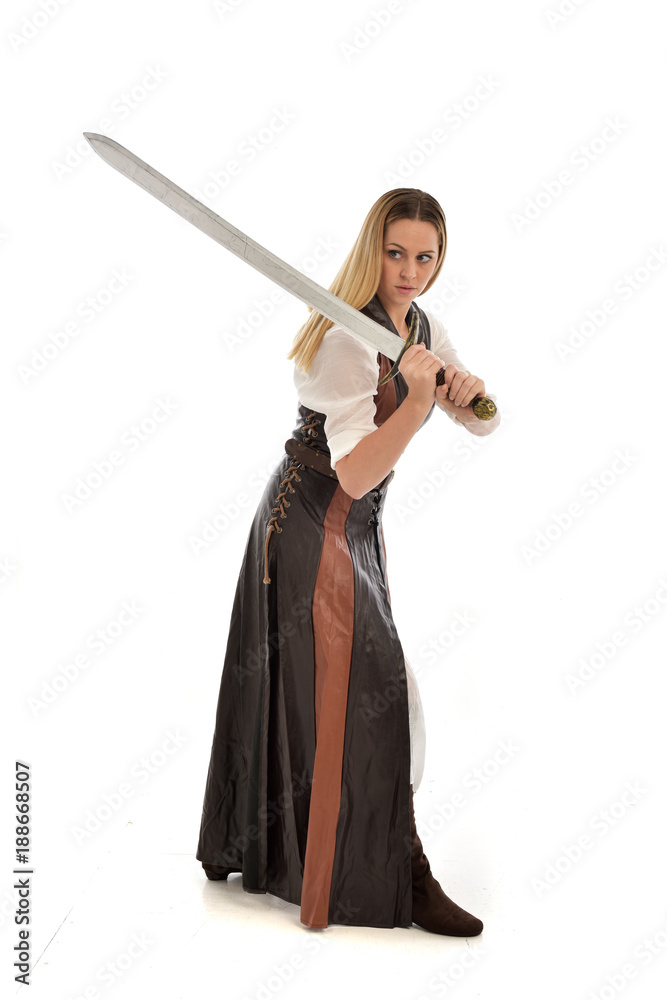 full length portrait of girl wearing brown fantasy costume, holding a sword. standing pose on white studio background. full length portrait of girl wearing brown fantasy costume, holding a sword. standing pose on white studio background.
