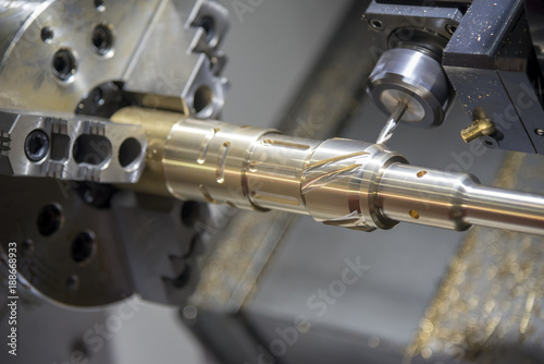 Close up of the CNC lathe (Turning machine)cutting brass shaft . Hi-precision CNC machining concept.