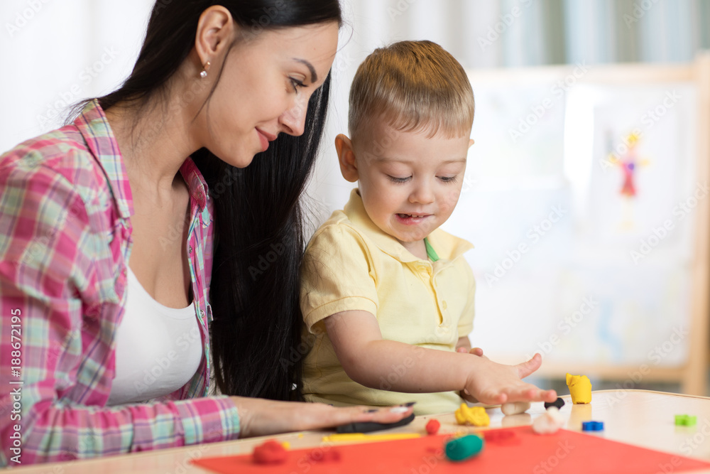 Family mother and kid boy molded from clay and play together at home. Concept of preschool or home education.