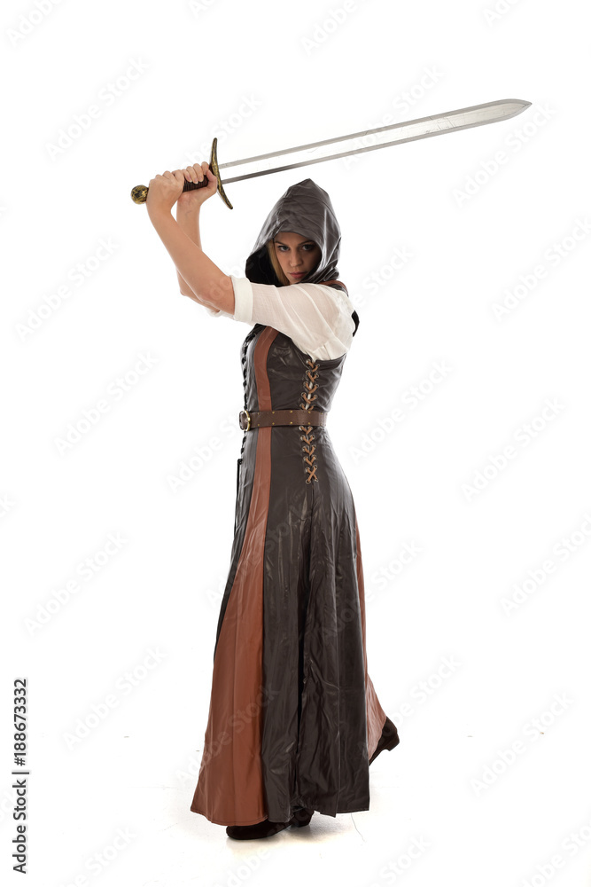 full length portrait of girl wearing brown fantasy costume, holding a sword. standing pose on white studio background. full length portrait of girl wearing brown fantasy costume, holding a sword. standing pose on white studio background.