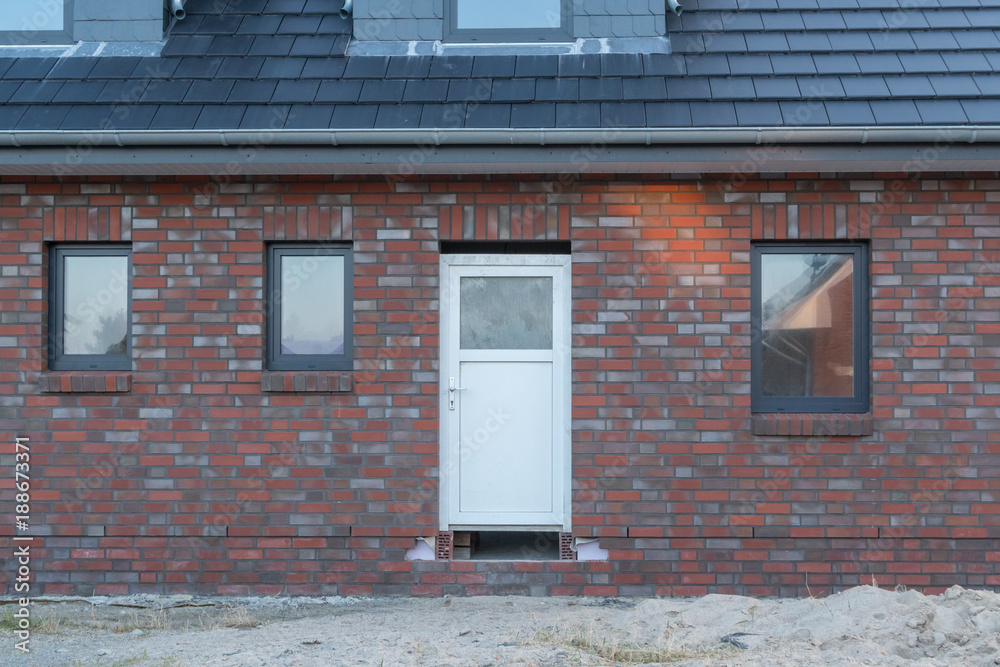 Fototapeta premium Weiße Haustür und anthrazite Fenster eines Hauses