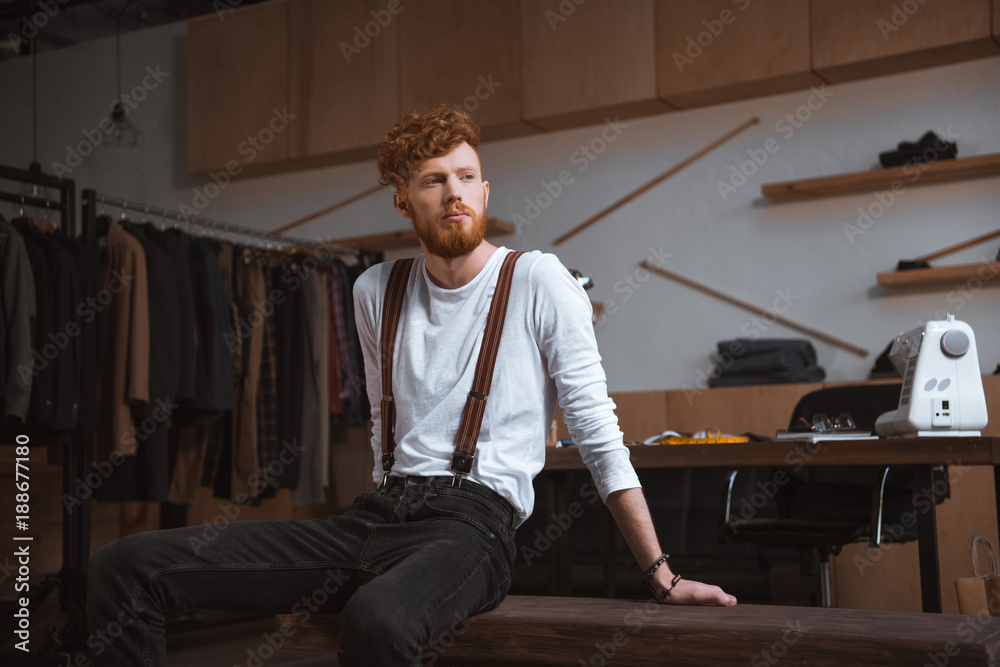 stylish young bearded fashion designer looking away in workshop stylish young bearded fashion designer looking away in workshop