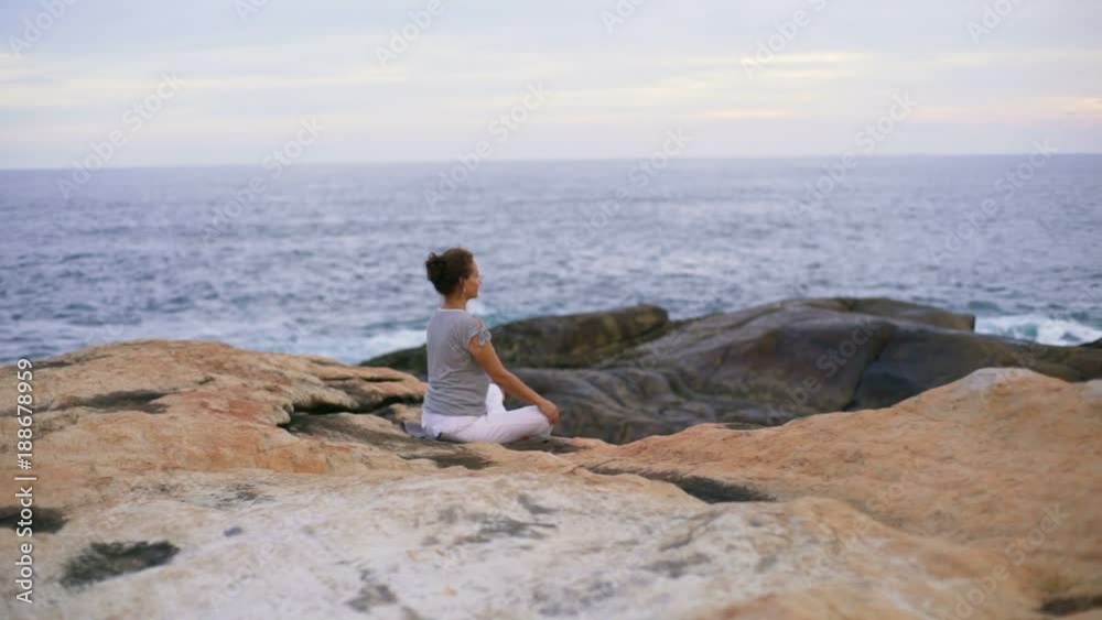 Woman meditate on rocky beach at sunset rapid slow motion Woman meditate on rocky beach at sunset rapid slow motion