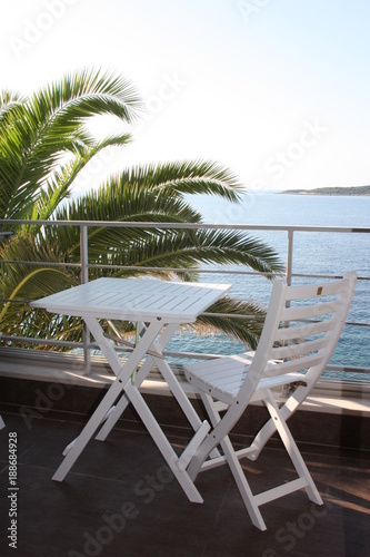 Still life at seaside with palm and table and chair