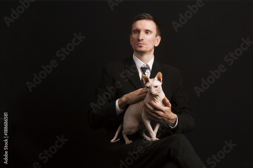 Fotografie cat sphinx lap of a guy in a suit on a black background