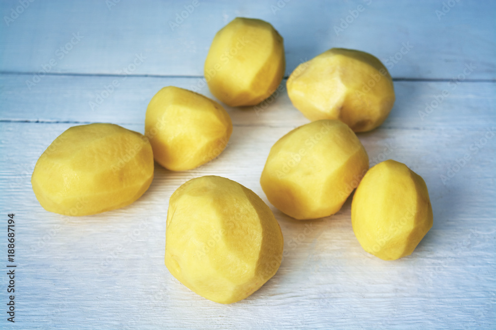 Raw peeled potatoes on white wooden background Raw peeled potatoes on white wooden background