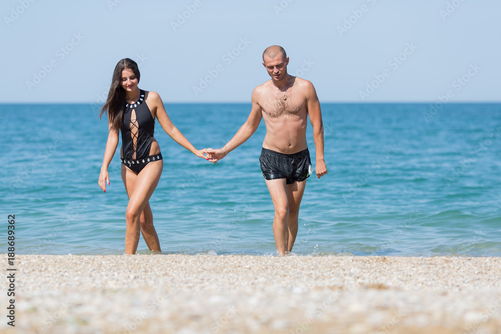 Attractive couple come from sea holding hands