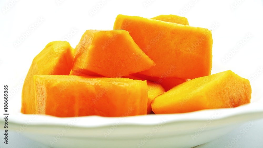 Cut ripe papaya put on blurry white plate - side view, close-up, and selective focus. Deliciously sweet high fibre fruit; rich sources of antioxidant nutrients. Cut ripe papaya put on blurry white plate - side view, close-up, and selective focus. Deliciously sweet high fibre fruit; rich sources of antioxidant nutrients.