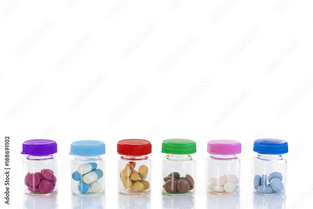 Medicine Concept: line of Medicine Tablets in glass Bottle with multi colored plastic caps on white background Medicine Concept: line of Medicine Tablets in glass Bottle with multi colored plastic caps on white background