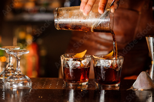 Bartender pouring alcoholic drink into the glasses photo