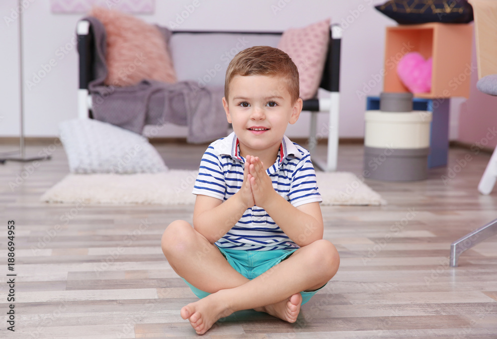 Cute little boy sitting on floor at home