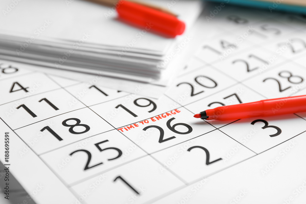 Calendar with written text TIME TO ENGAGE and felt-tip pen, closeup Calendar with written text TIME TO ENGAGE and felt-tip pen, closeup
