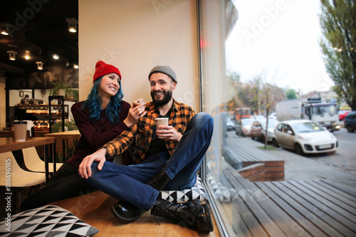 Young hipster couple resting near window in cafe