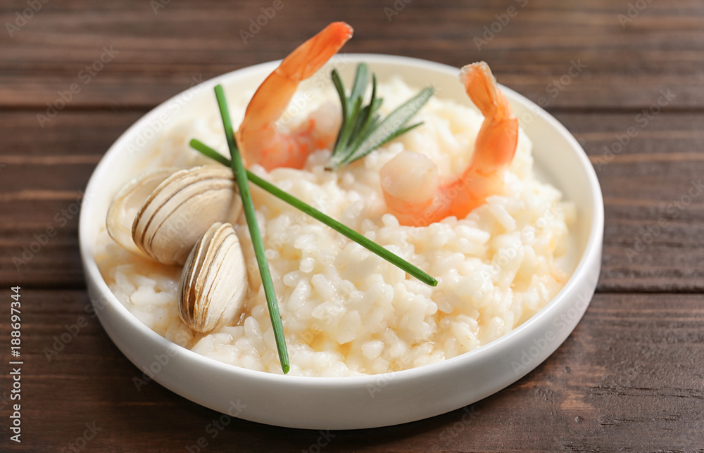 Plate with delicious seafood risotto on wooden table