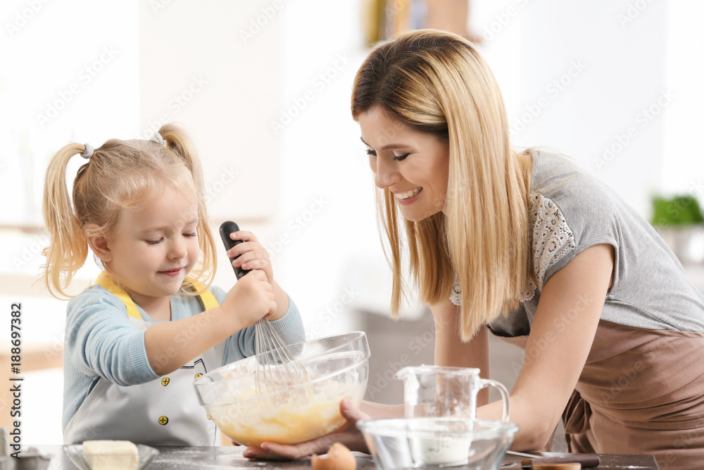 Mother and daughter preparing dough indoors Mother and daughter preparing dough indoors