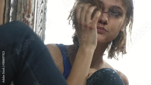A beat-up girl feels sorry for herself sitting by the mirror