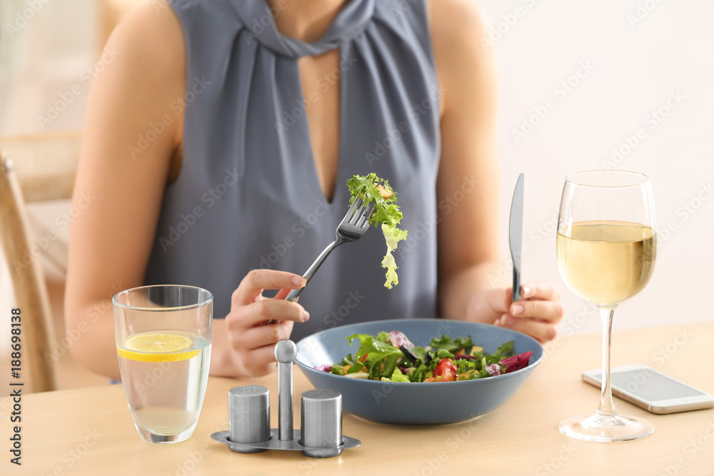 Young woman eating fresh salad at table Young woman eating fresh salad at table