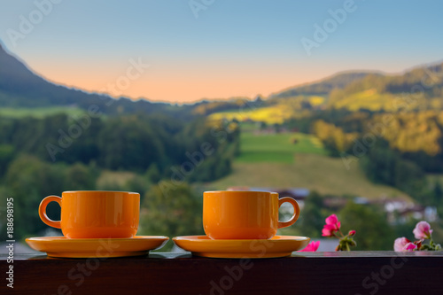 Two orange cups on a terrace against mountain landscape