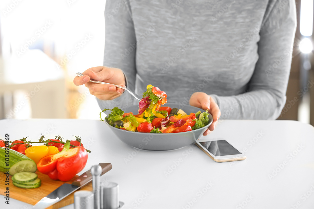 Young woman eating fresh salad at table Young woman eating fresh salad at table