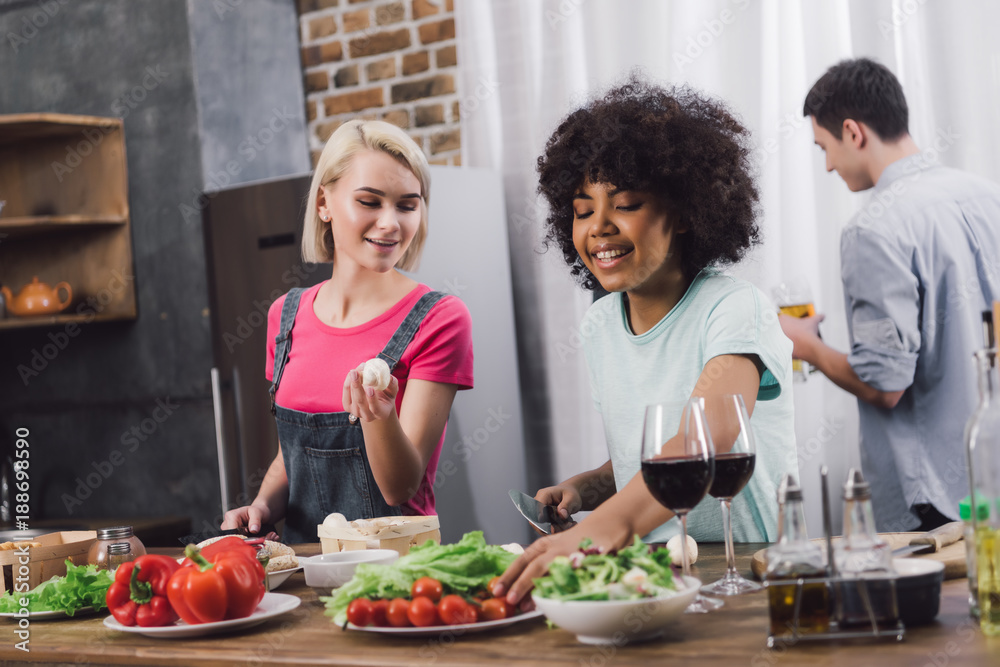 smiling multiethnic girls cooking in kitchen