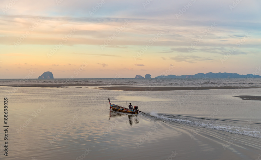 Fisherman is riding the long tail boat to the andaman ocean in early morning with beautiful scenery at Pakmeng beach, Trang province, Thailand.