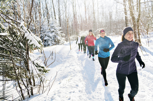 Group of friends enjoying jogging in the snow in winter photo