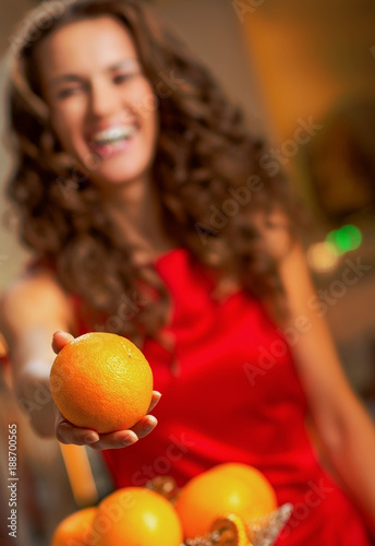 Closeup on happy young housewife giving orange