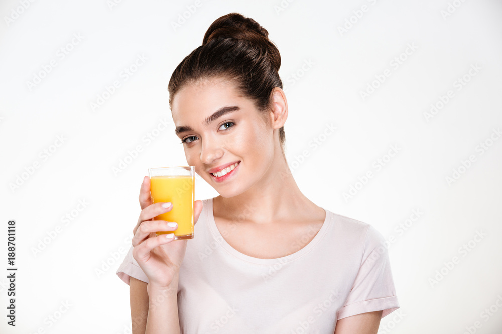 Close up picture of glad gorgeous woman drinking sweet orange juice from transparent glass with smile over white background Close up picture of glad gorgeous woman drinking sweet orange juice from transparent glass with smile over white background