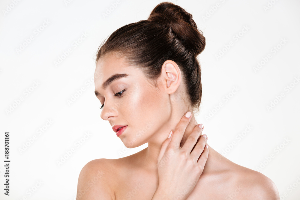 Portrait of gentle young woman with healthy body touching her neck posing over white background with face downwards Portrait of gentle young woman with healthy body touching her neck posing over white background with face downwards