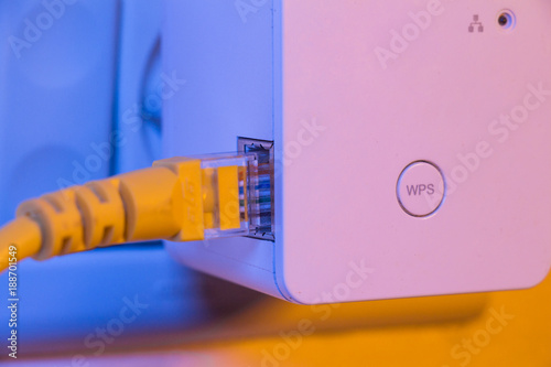 WiFi extender in electrical socket on the wall with ethernet cable plugged in