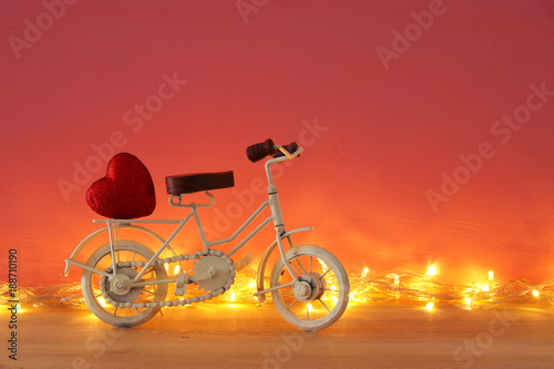 Valentine's day romantic background with white vintage bicycle toy and heart on it over wooden table.