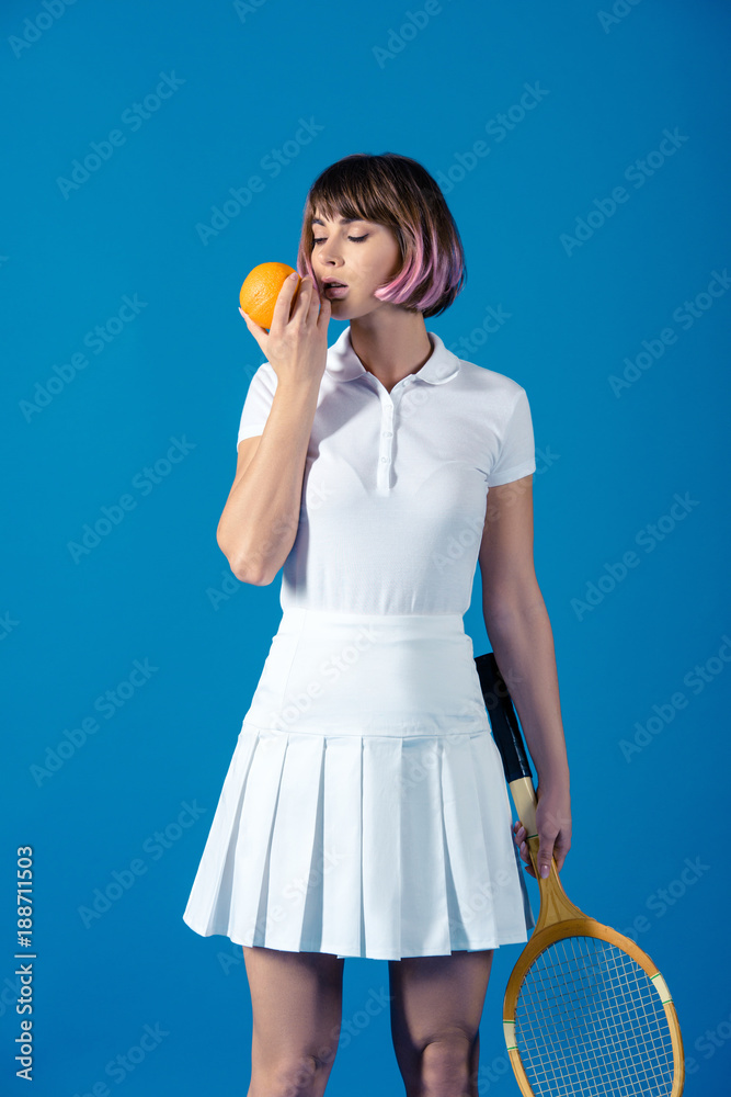 sexy Tennis player standing with orange isolated on blue sexy Tennis player standing with orange isolated on blue