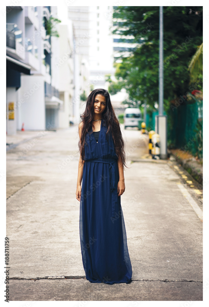 Portrait of young Indian Asian woman standing in the middle of the street wearing a long blue dress looking at the camera. Portrait of young Indian Asian woman standing in the middle of the street wearing a long blue dress looking at the camera.
