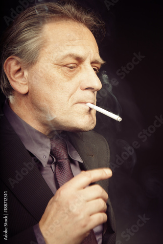 Older caucasian man trying electronic cigarette on black background