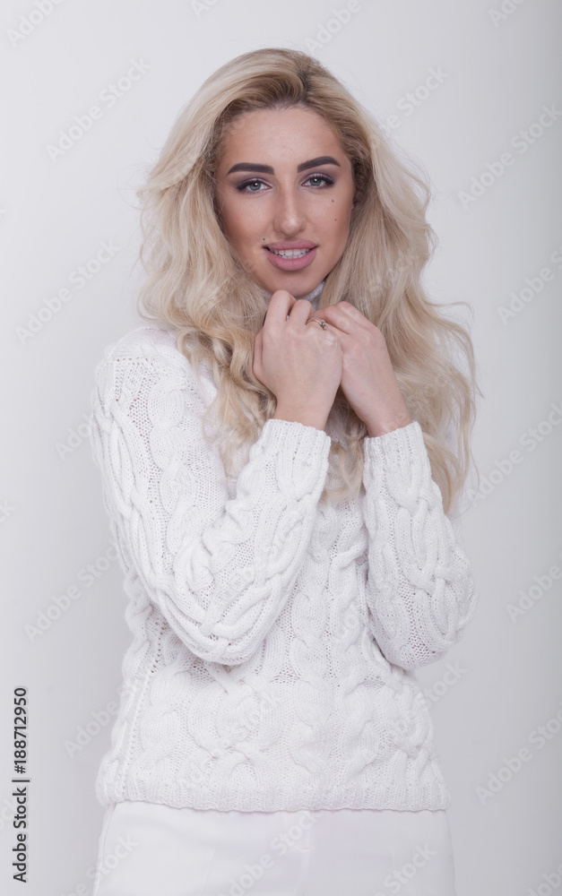 Studio portrait of beautiful long-haired blonde woman in hot sweater on white background Studio portrait of beautiful long-haired blonde woman in hot sweater on white background