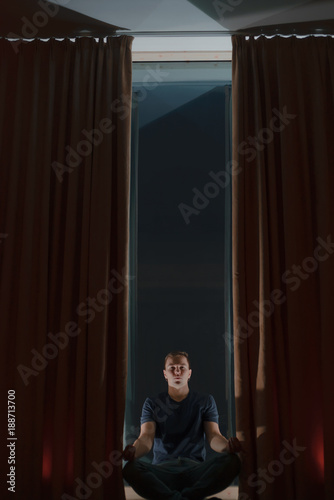 dark room, the boy is doing yoga