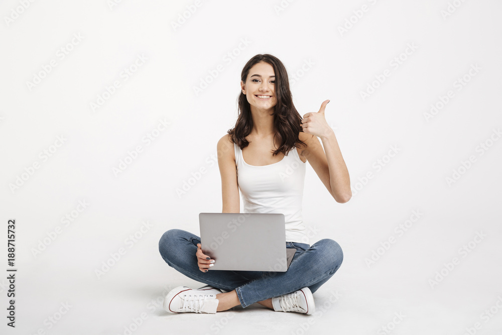 Portrait of a happy girl dressed in tank-top holding laptop